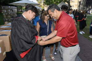 费利克斯·瓦斯奎斯Felix Vasquez在开学典礼前帮助儿子马修Mathew穿上长袍。 （南加州大学照片/古斯·鲁埃拉斯Gus Ruelas）